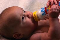 Picture of a baby feeding himself a bottle