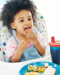 Picture of a young boy feeding himself from his highchair