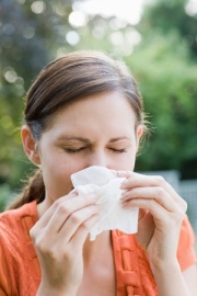 Photo of a woman sneexing into a tissue